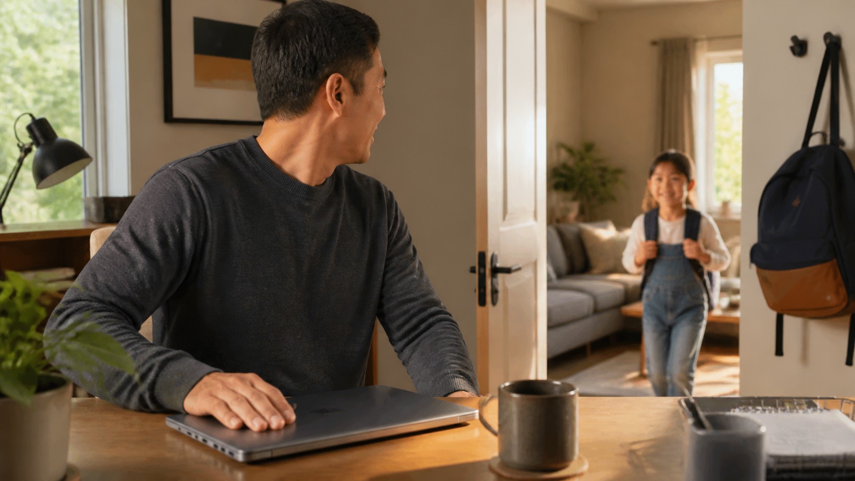 Parent closing a laptop at home as a child enters the room after school.